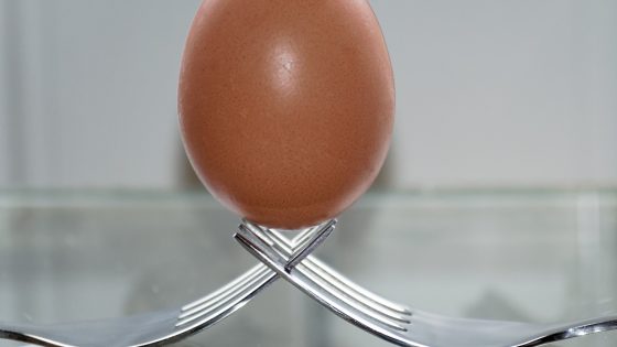 Ein Ei aufrecht auf zwei verschränkten Gabeln stehend