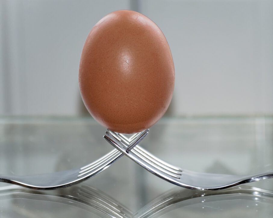 Ein Ei aufrecht auf zwei verschränkten Gabeln stehend
